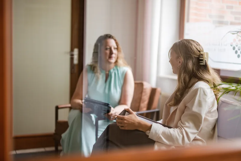Zwei Frauen schauen gemeinsam auf ein Tablet in einem freundlichen Wartebereich der Kanzlei RKK
